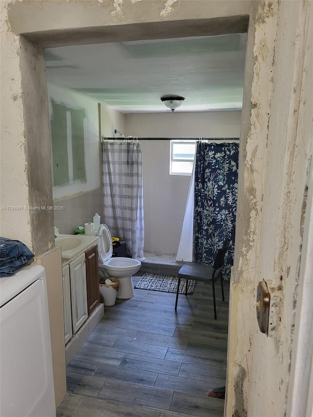 bathroom with wood finished floors, toilet, vanity, curtained shower, and washer / clothes dryer