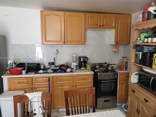 kitchen with stainless steel microwave, backsplash, gas range, and light countertops