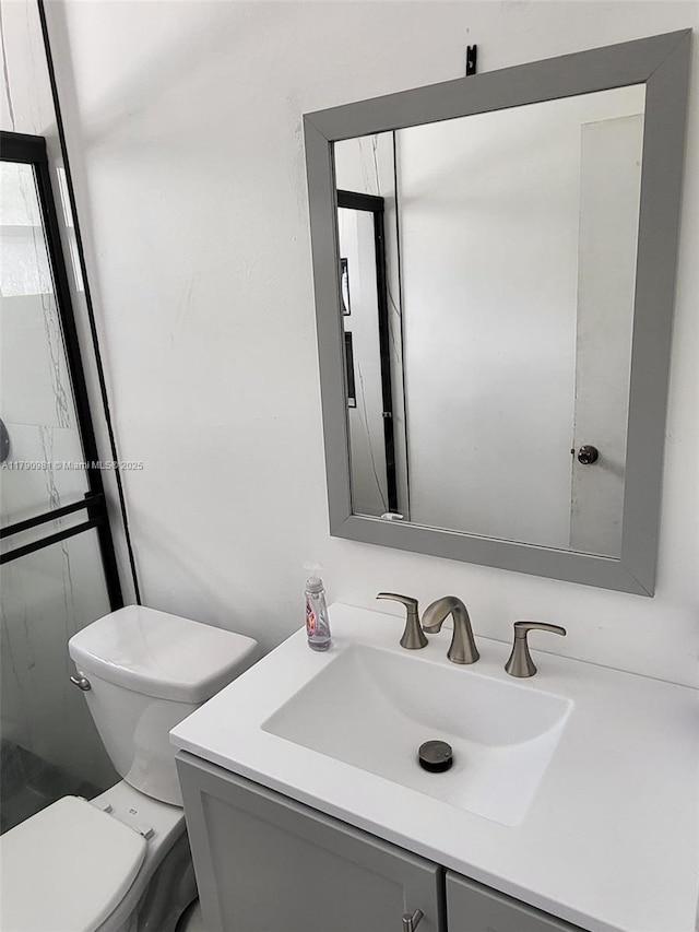 bathroom with toilet, a shower, and vanity