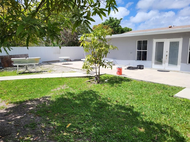 view of yard with fence, a patio area, and french doors