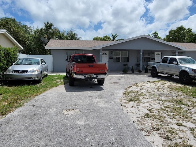 ranch-style house featuring driveway and fence