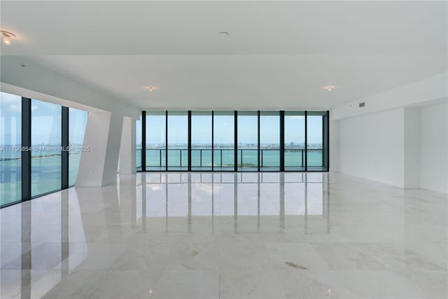 unfurnished room with marble finish floor, expansive windows, and french doors