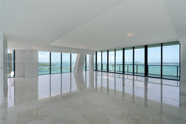unfurnished room featuring a water view and expansive windows