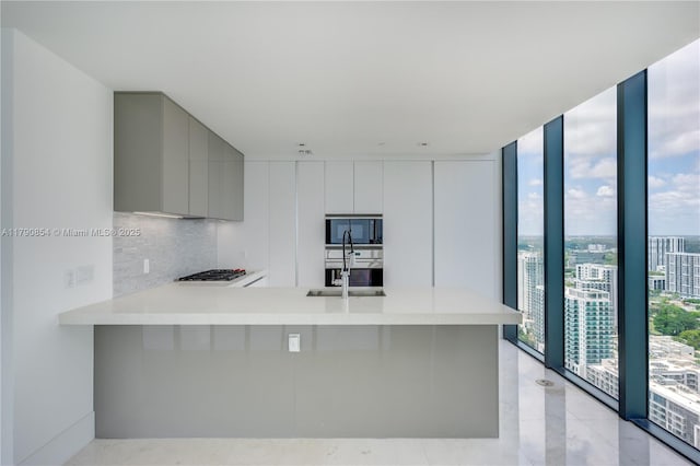 kitchen featuring black microwave, gray cabinetry, a wall of windows, modern cabinets, and a peninsula
