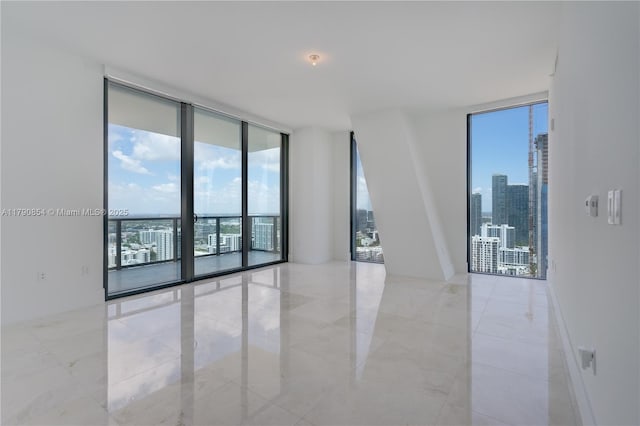 unfurnished room featuring a view of city, light tile patterned flooring, a wall of windows, and plenty of natural light
