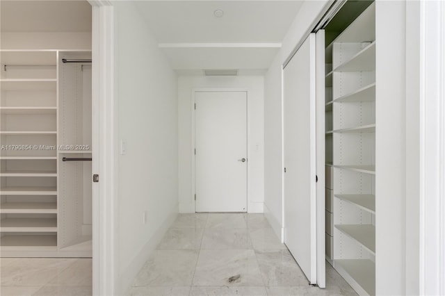 hall with visible vents, marble finish floor, and baseboards