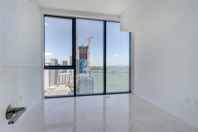 empty room with a view of city, a water view, tile patterned flooring, and expansive windows
