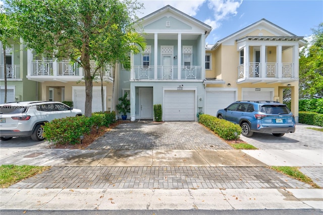 view of property featuring driveway, a balcony, stucco siding, and an attached garage