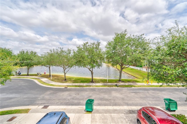 view of street featuring sidewalks, a water view, and curbs
