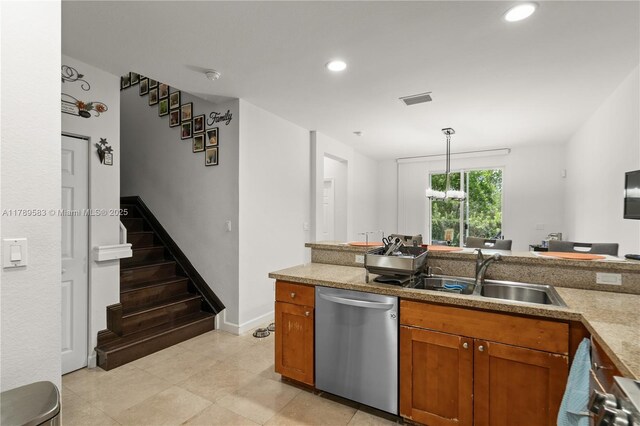 kitchen featuring stainless steel dishwasher, brown cabinetry, decorative light fixtures, a sink, and visible vents