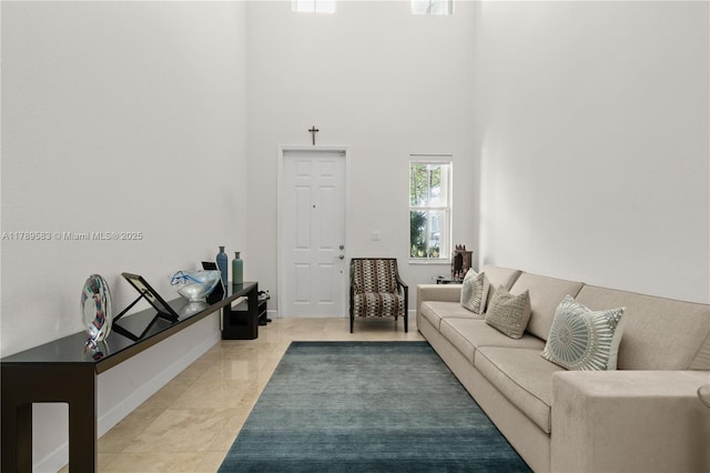 living area featuring baseboards, light tile patterned floors, and a towering ceiling