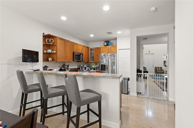 kitchen featuring baseboards, visible vents, stainless steel appliances, and a peninsula