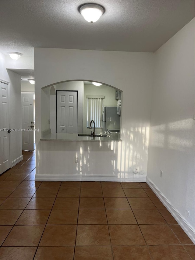 7985 NW 8th St Unit 110A, Miami, FL 33126 - tiled empty room with a textured ceiling, a sink, arched walkways, and baseboards