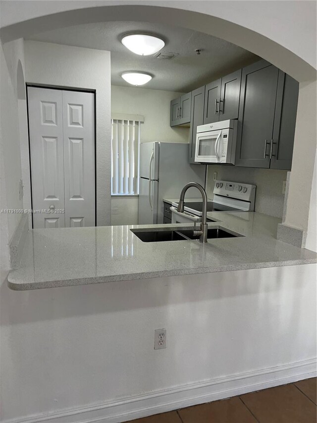 7985 NW 8th St Unit 110A, Miami, FL 33126 - kitchen featuring white appliances, a peninsula, arched walkways, and light stone countertops