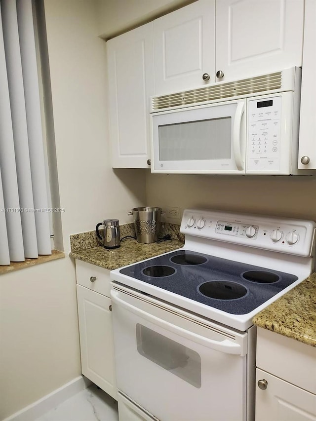 kitchen with baseboards, white cabinets, white appliances, and light stone counters