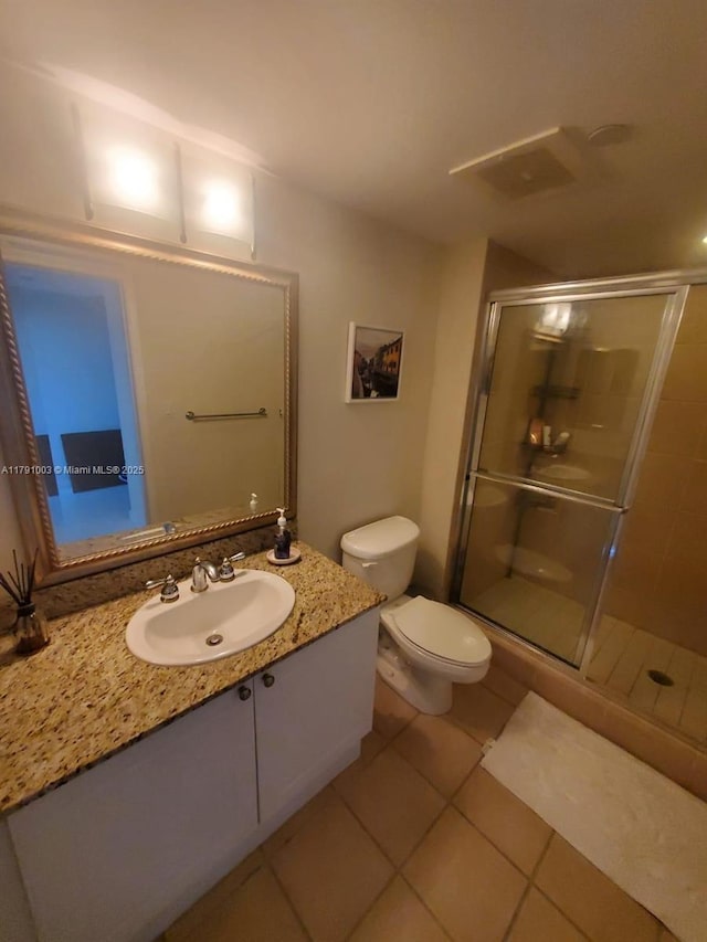 bathroom with tile patterned flooring, vanity, toilet, and a shower stall
