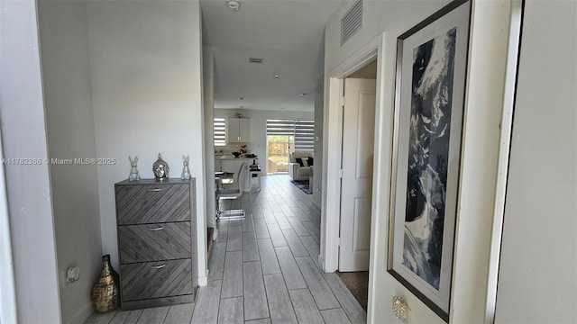 hall with baseboards, visible vents, and wood tiled floor