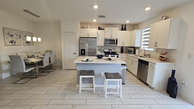 kitchen featuring a sink, white cabinets, appliances with stainless steel finishes, and a kitchen island