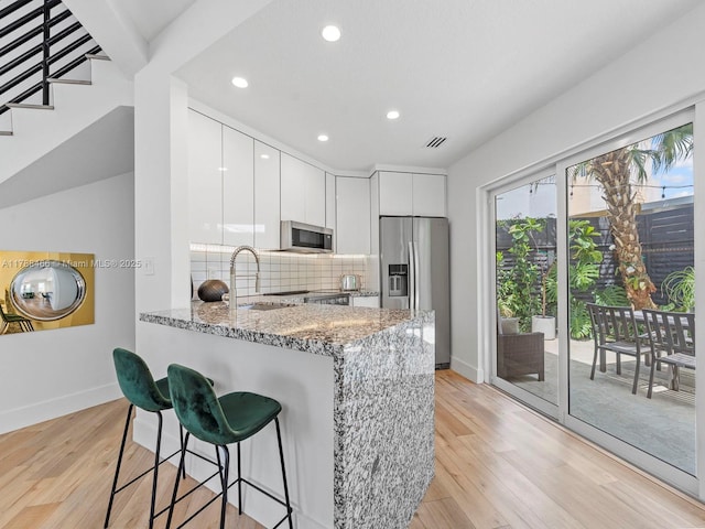 3025 SW 13th St, Miami, FL 33145 - kitchen featuring stainless steel appliances, light stone counters, modern cabinets, baseboards, and light wood finished floors