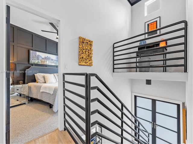 staircase with a towering ceiling, wood finished floors, and a ceiling fan