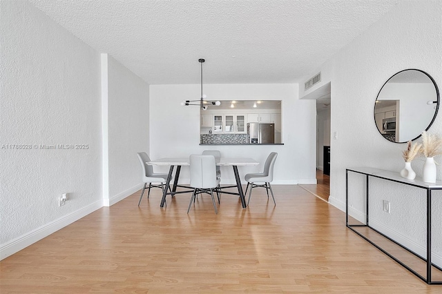 19390 Collins Ave Unit 1501, Sunny Isles Beach, FL 33160 - dining area with a textured ceiling, a chandelier, light wood finished floors, and a textured wall