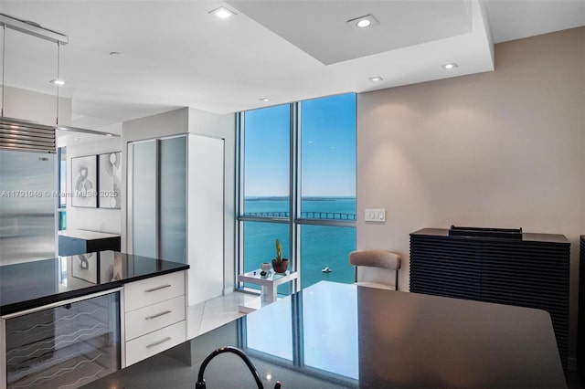 office with recessed lighting, a water view, expansive windows, and beverage cooler
