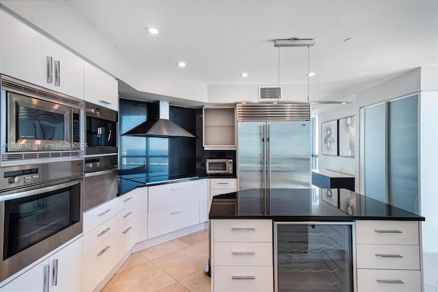 kitchen with modern cabinets, built in appliances, wall chimney exhaust hood, dark countertops, and beverage cooler