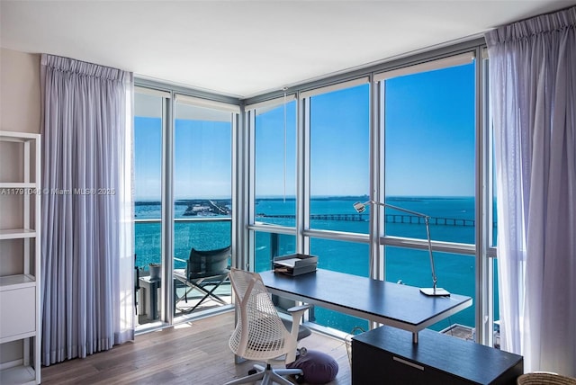 office area with a water view, expansive windows, and wood finished floors