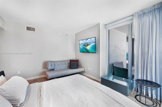 bedroom featuring baseboards, visible vents, and wood finished floors