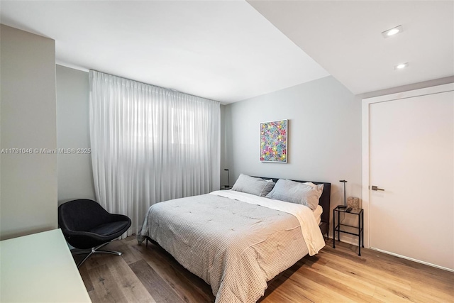 bedroom featuring baseboards, light wood-type flooring, and recessed lighting