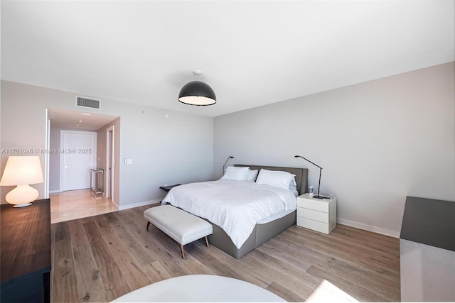 bedroom with visible vents, wood finished floors, and baseboards