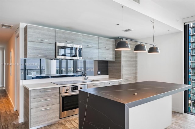 kitchen with stainless steel appliances, light wood-type flooring, a sink, visible vents, and modern cabinets