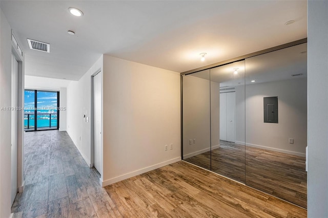 unfurnished bedroom with visible vents, wood finished floors, electric panel, and baseboards