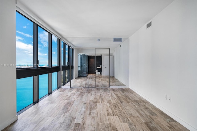 interior space featuring baseboards, visible vents, wood finished floors, and floor to ceiling windows