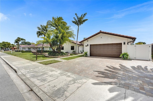 ranch-style house with a front lawn, driveway, an attached garage, and stucco siding