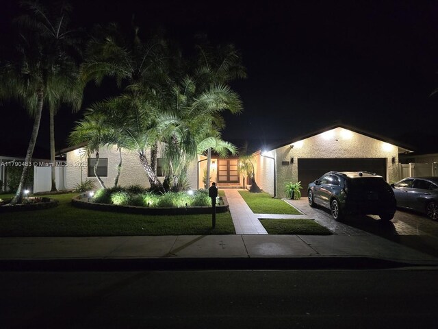view of front facade with a garage, stucco siding, driveway, and a yard