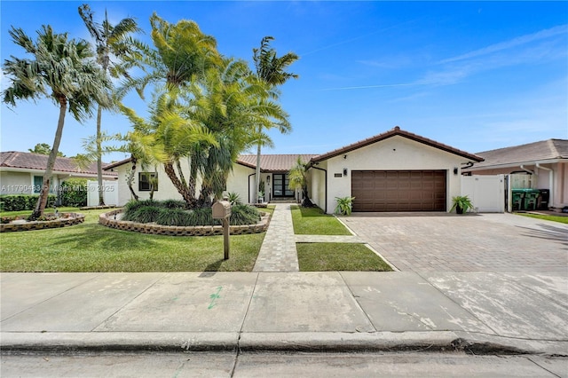 ranch-style house with a tile roof, a front lawn, stucco siding, driveway, and an attached garage