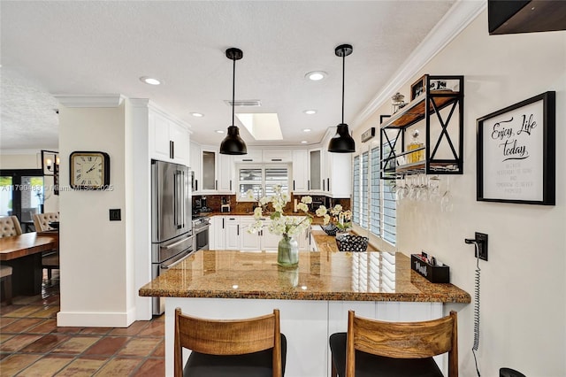 kitchen with appliances with stainless steel finishes, a wealth of natural light, visible vents, and a peninsula