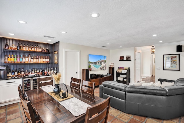 dining area with a textured ceiling, visible vents, recessed lighting, and indoor bar