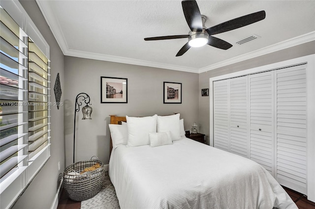 bedroom with ornamental molding, a closet, visible vents, and wood finished floors