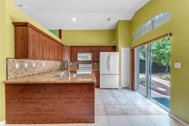 kitchen with a sink, tasteful backsplash, visible vents, a peninsula, and white appliances