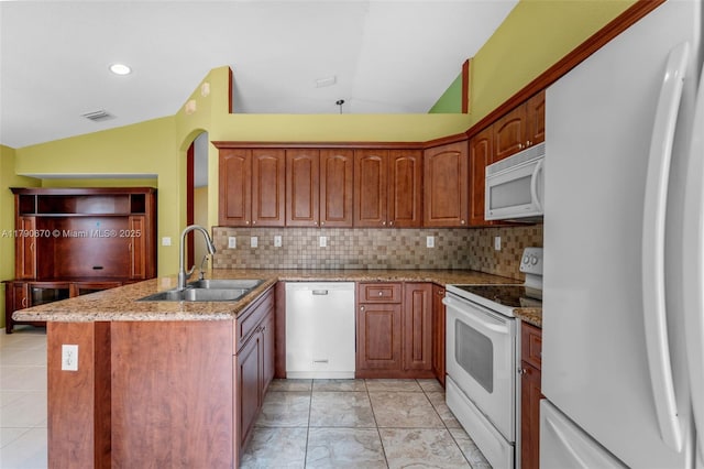 kitchen featuring white appliances, a sink, visible vents, vaulted ceiling, and a peninsula