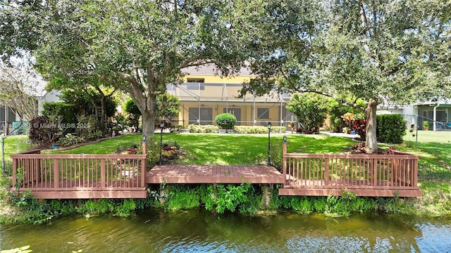 back of property featuring a lawn and a deck with water view