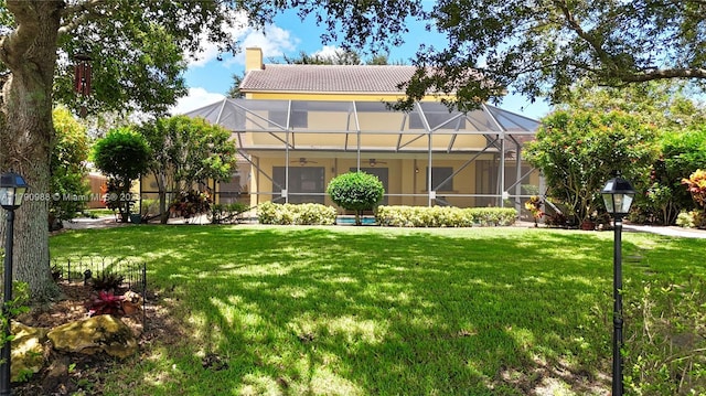 view of front facade featuring stucco siding, ceiling fan, a chimney, and a front lawn