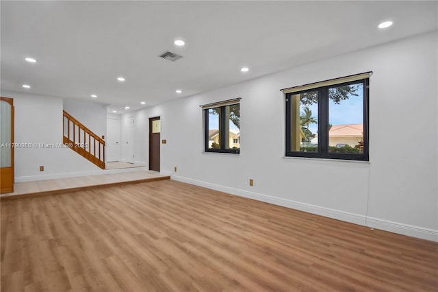 unfurnished living room featuring light wood finished floors, recessed lighting, stairs, and visible vents