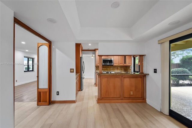 14950 Featherstone Way, Davie, FL 33331 - kitchen with appliances with stainless steel finishes, a peninsula, light wood finished floors, brown cabinetry, and a sink