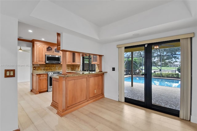 14950 Featherstone Way, Davie, FL 33331 - kitchen featuring appliances with stainless steel finishes, light wood-style floors, a peninsula, decorative backsplash, and recessed lighting