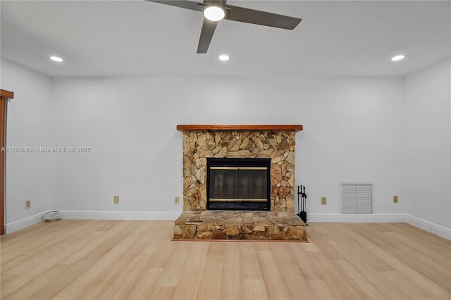 unfurnished living room featuring visible vents, wood finished floors, a fireplace, baseboards, and ceiling fan
