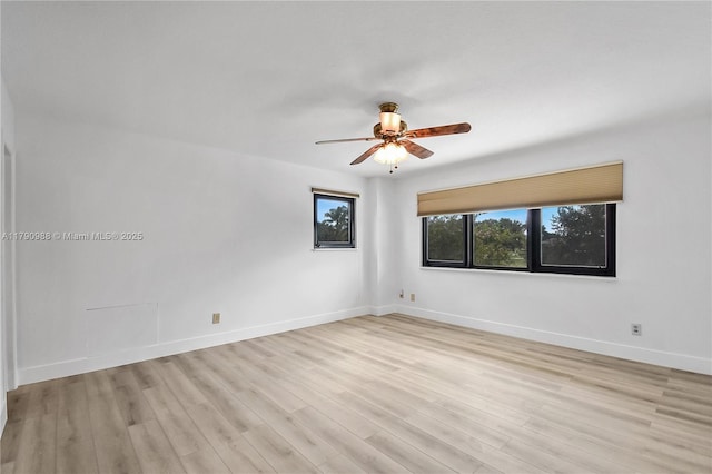 empty room featuring light wood-type flooring, a ceiling fan, and baseboards