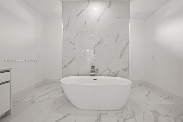 full bathroom featuring baseboards, a freestanding tub, vanity, and marble finish floor